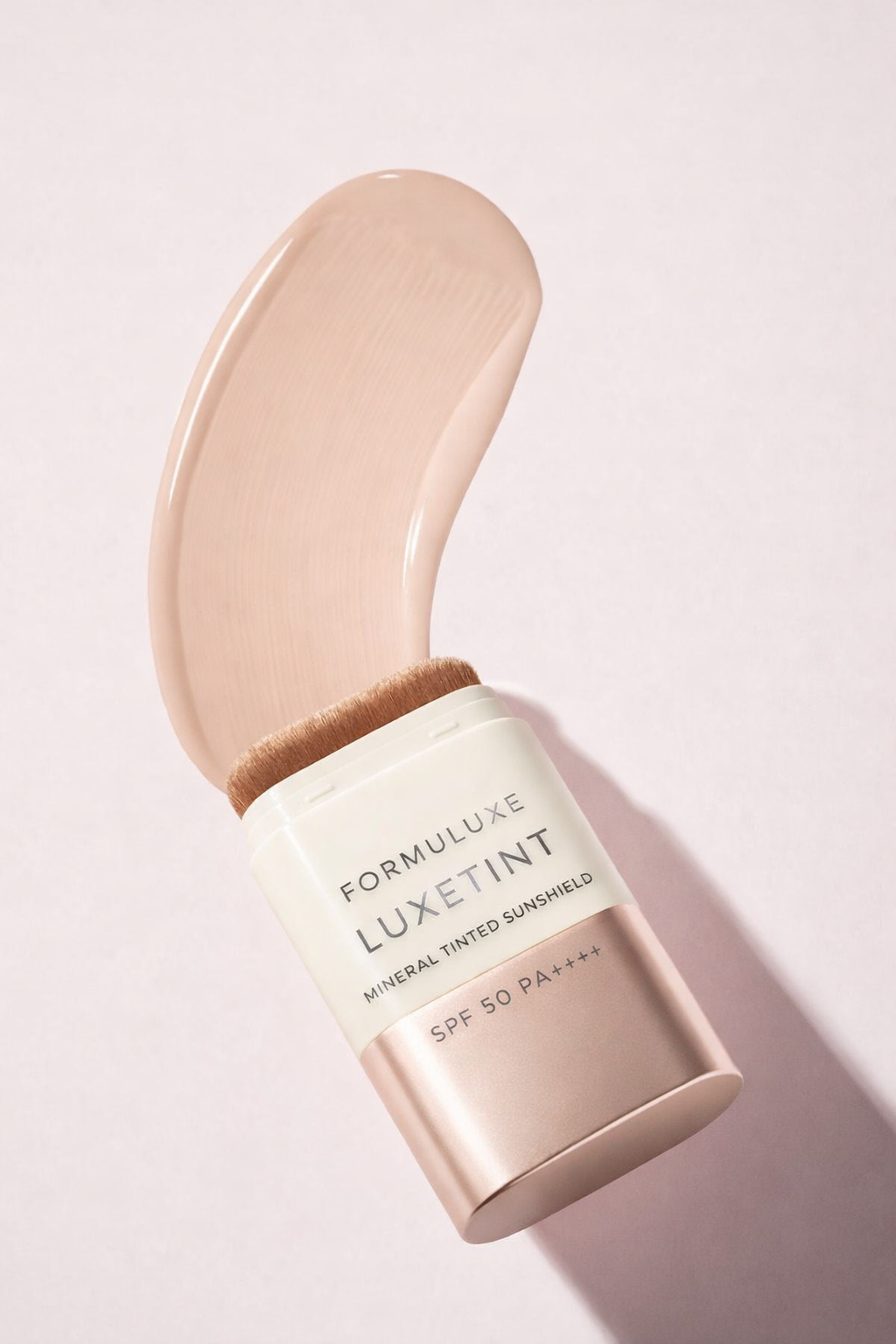Formuluxe Luxetint makeup product with applicator on a light pink background