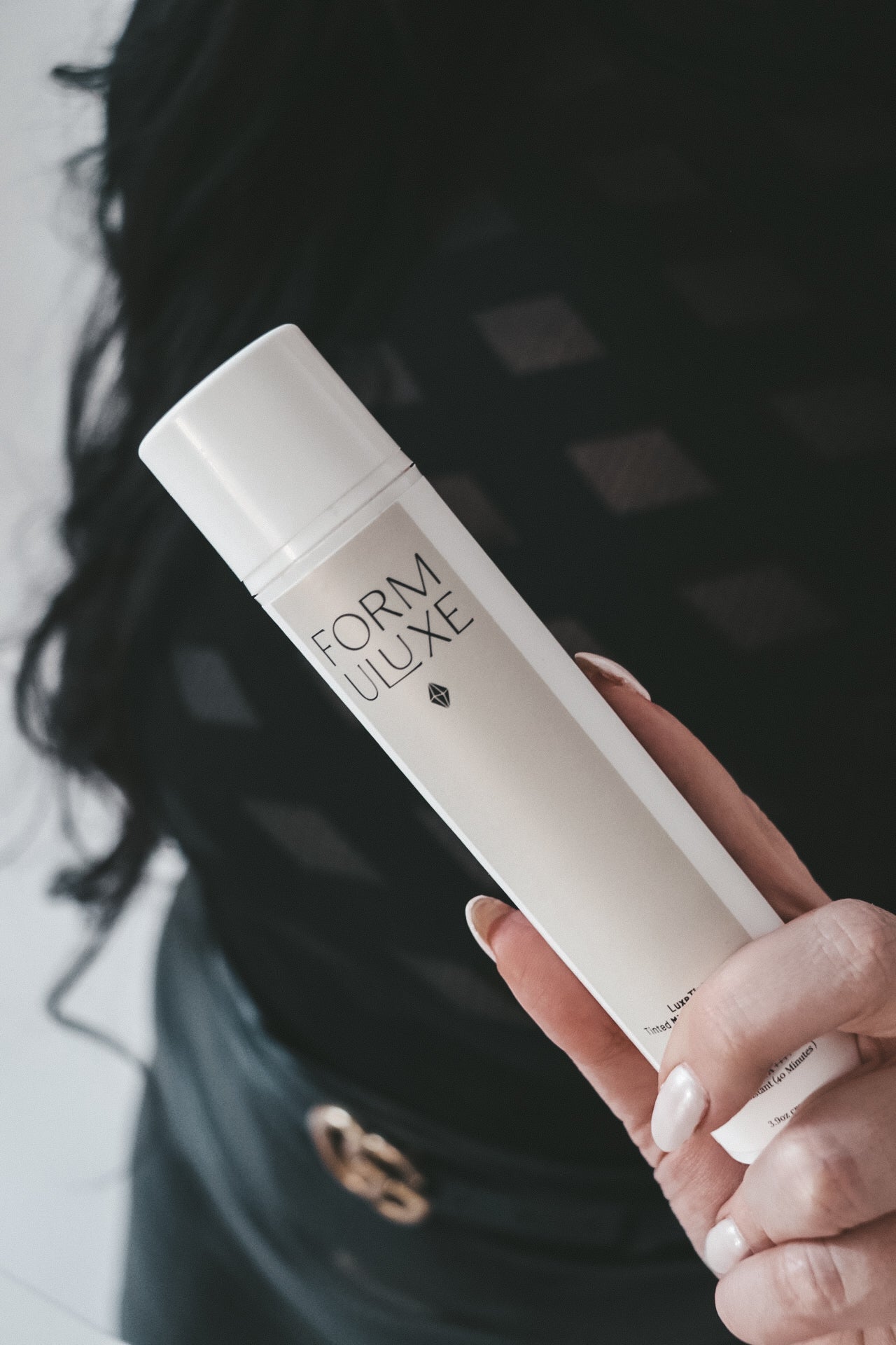Hand holding a Form Uluxe product with a blurred background