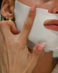 Person applying a white facial mask to their face