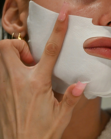 Person applying a white facial mask to their face