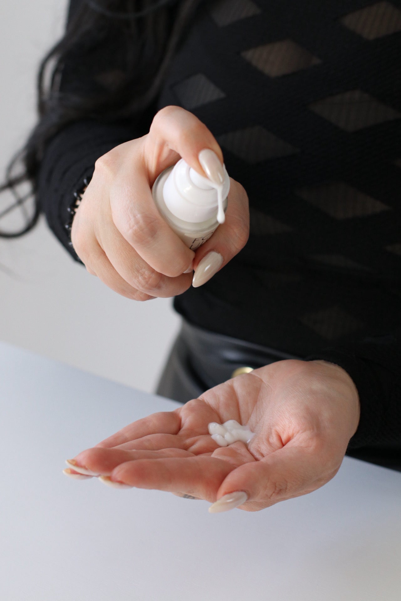 Person holding a white bottle of lotion with a blurred background