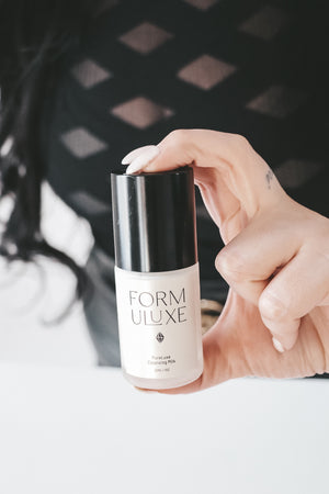 Hand holding a Formuluxe skincare product with a blurred background
