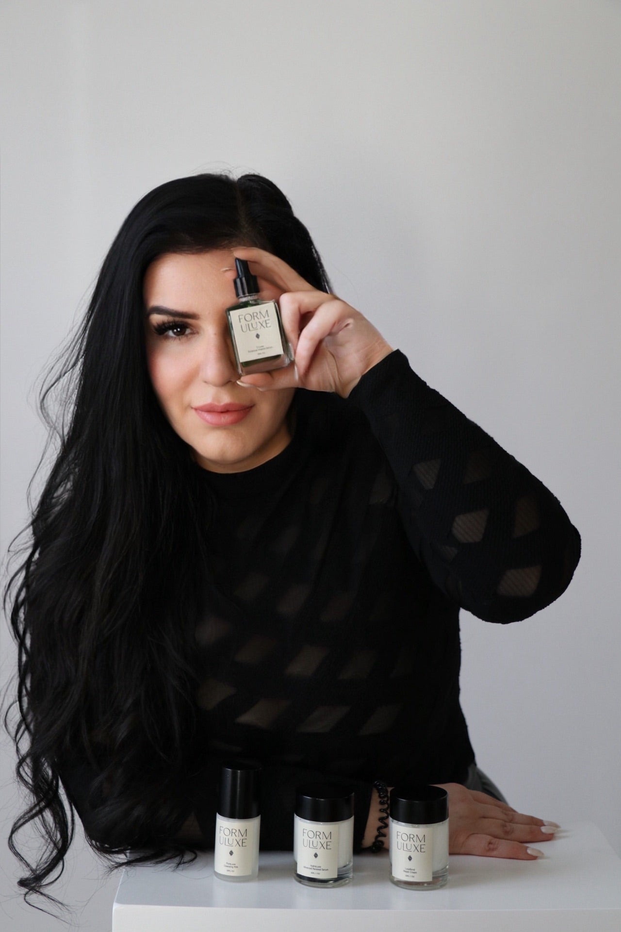 Woman holding a skincare product with other products on a table