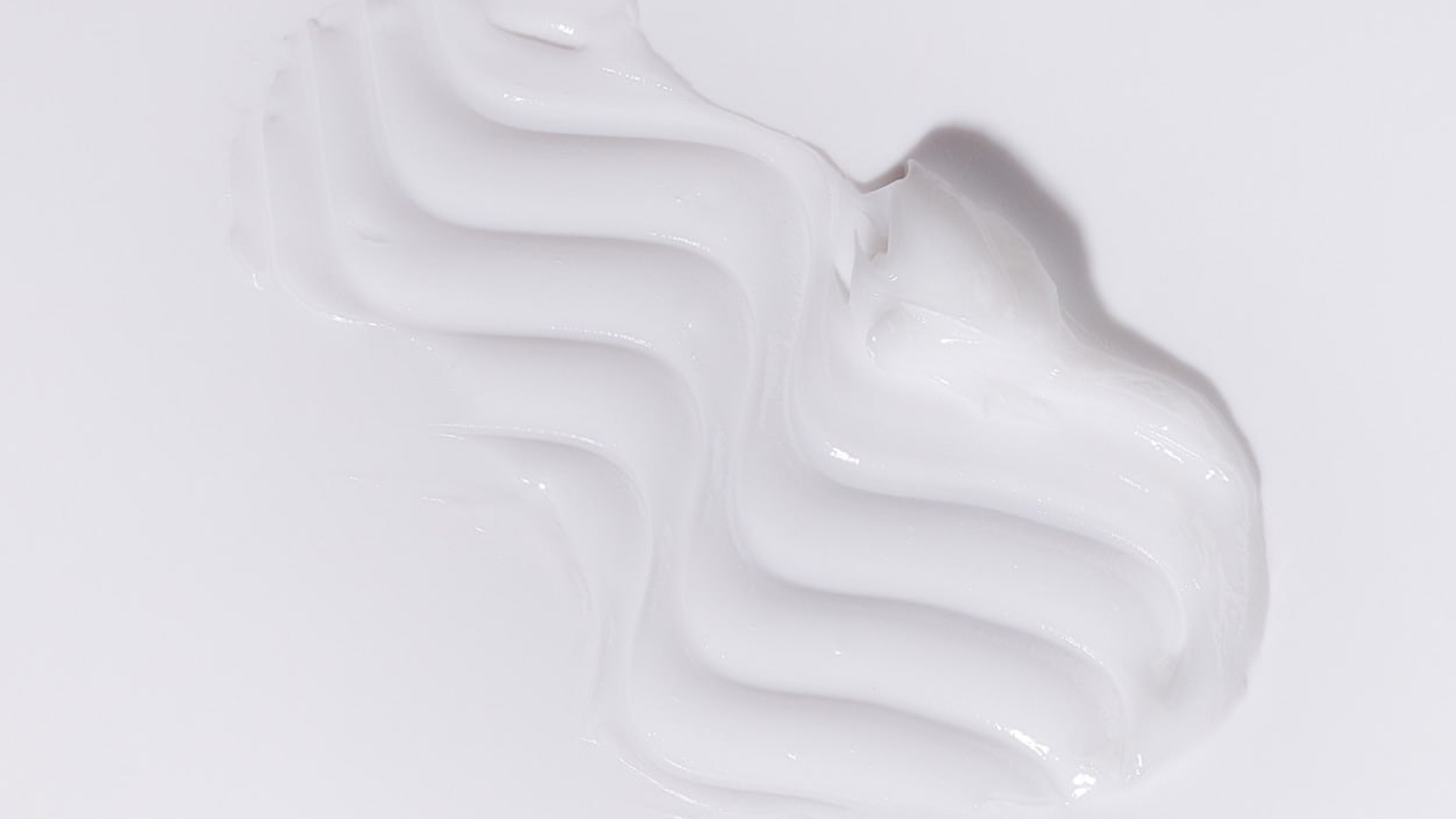 Close-up of white cream or paint on a light gray background