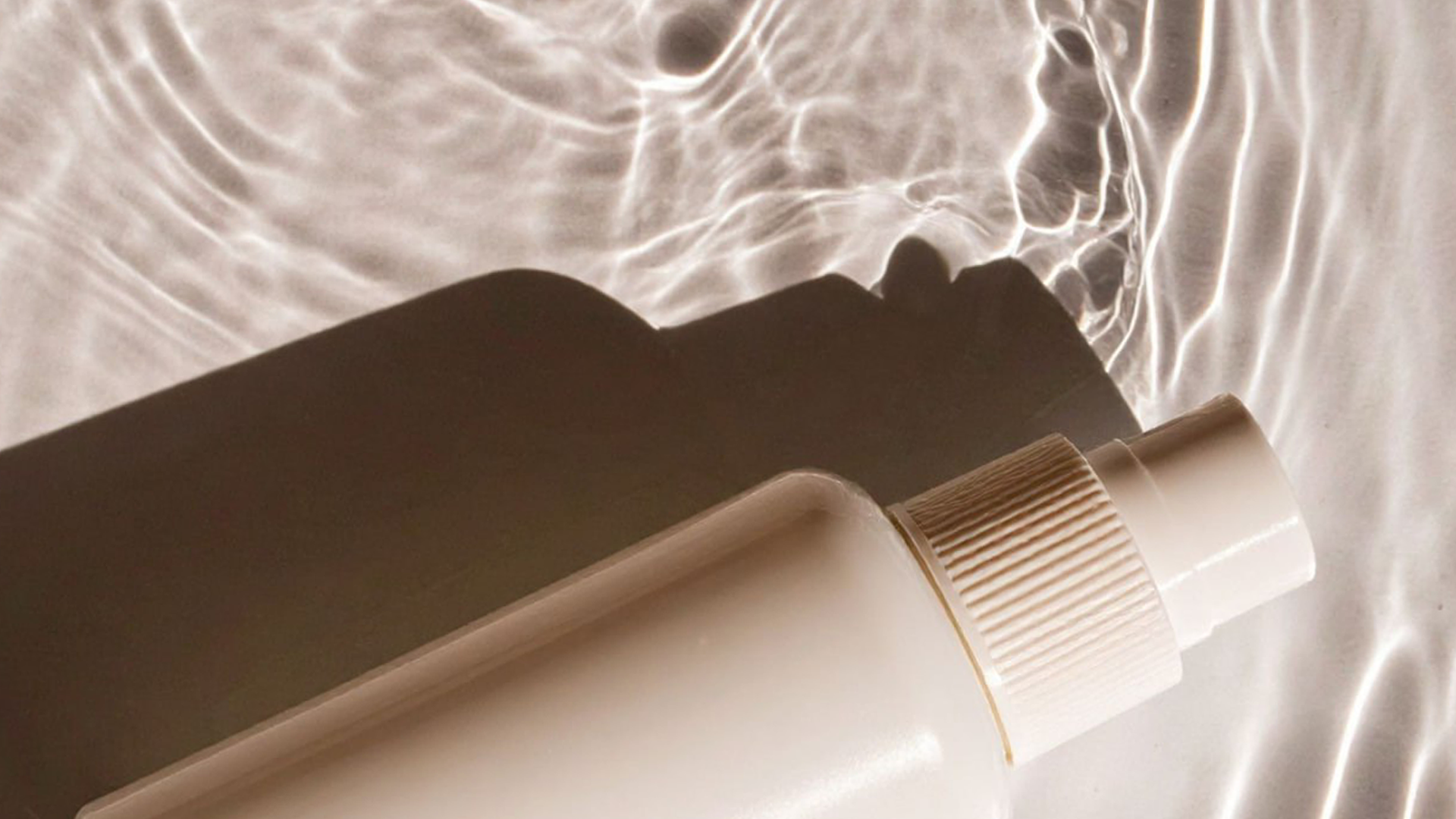 Cosmetic bottle with pump on a textured beige background